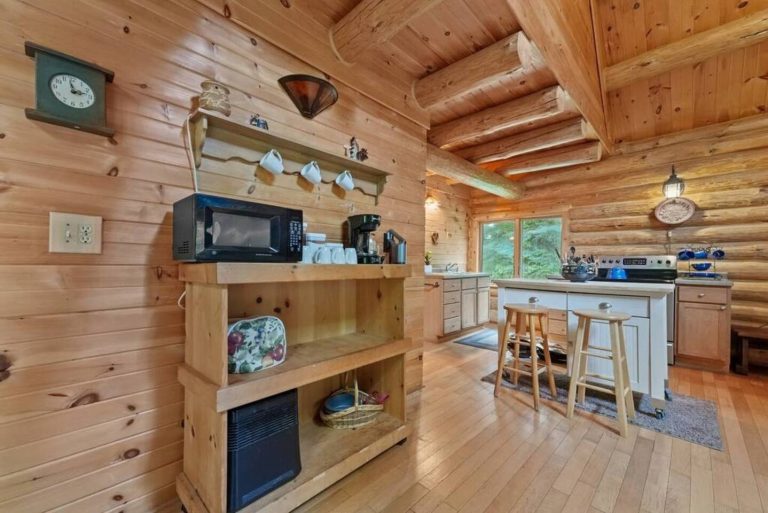 Log cabin kitchen and island seating in this Evart, Michigan cabin — Coyote Fire Retreat, hosted by Roam