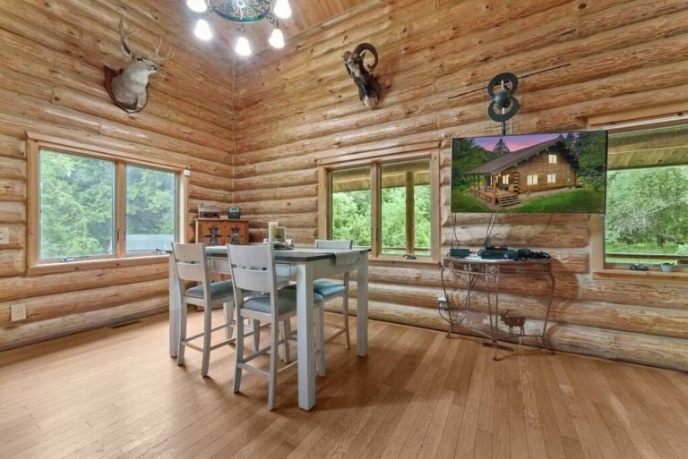 Dining table with wall-mounted TV in log cabin in Evart, Michigan — Coyote Fire Retreat, hosted by Roam