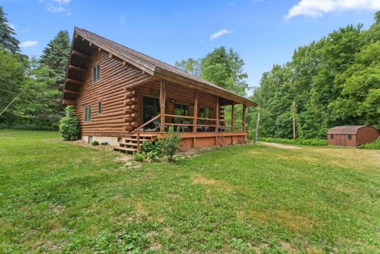 Log cabin exterior with covered porch and yard in Evart, Michigan — Coyote Fire Retreat, hosted by Roam