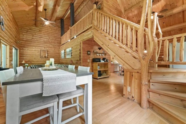 Dining nook beneath rustic log staircase in Evart, Michigan — Coyote Fire Retreat, hosted by Roam