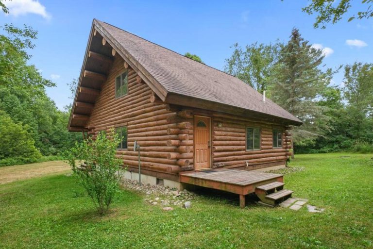 Log cabin exterior with covered entry deck in Evart, Michigan — Coyote Fire Retreat, hosted by Roam
