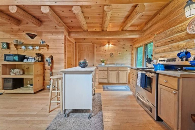 Log cabin kitchen with island and gas range in Evart, Michigan — Coyote Fire Retreat, hosted by Roam