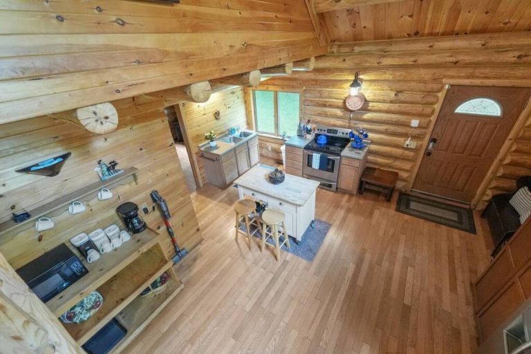 Overhead loft view of log cabin kitchen and front door in Evart, Michigan — Coyote Fire Retreat, hosted by Roam