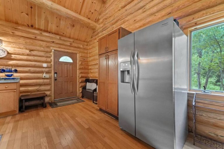 Log cabin entryway with stainless refrigerator in this Evart, Michigan cabin — Coyote Fire Retreat, hosted by Roam
