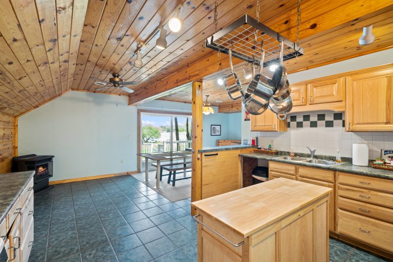 Kitchen with hanging pot rack and tile floor in Reed City, Michigan house — Lakeside Lodge Retreat, hosted by Roam