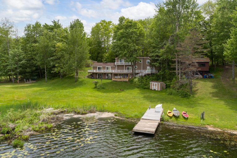 Lakefront yard with dock and kayaks House in Reed City, Michigan — Lakeside Lodge Retreat, hosted by Roam