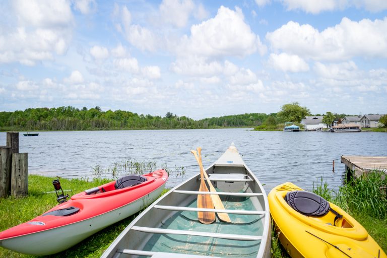 Kayaks and canoe on the lake shore in Reed City, Michigan — Lakeside Lodge Retreat, hosted by Roam