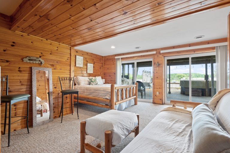 Wood-paneled bedroom with deck access House in Reed City, Michigan — Lakeside Lodge Retreat, hosted by Roam