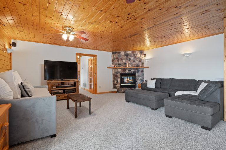 Living room with stone fireplace and TV in Reed City, Michigan house — Lakeside Lodge Retreat, hosted by Roam