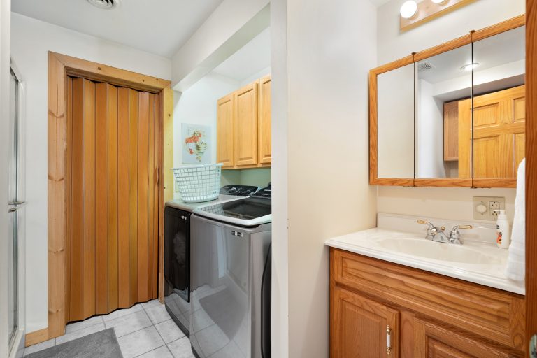 Laundry room and bathroom vanity in Reed City, Michigan house — Lakeside Lodge Retreat, hosted by Roam