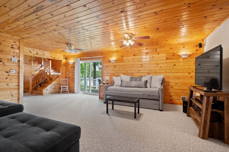 Lower-level den with daybed and TV in Reed City, Michigan house — Lakeside Lodge Retreat, hosted by Roam