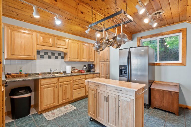 Kitchen with pot rack and stainless fridge in Reed City, Michigan house — Lakeside Lodge Retreat, hosted by Roam