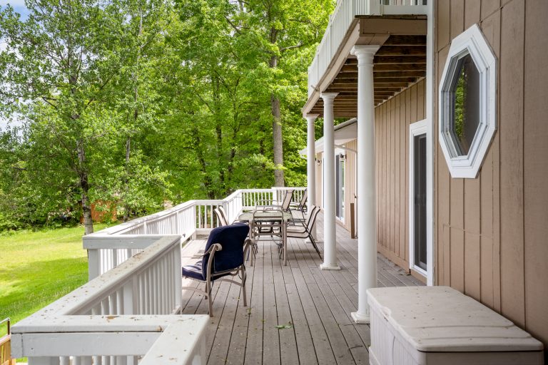 Covered deck with patio dining and lounge chairs House in Reed City, Michigan — Lakeside Lodge Retreat, hosted by Roam