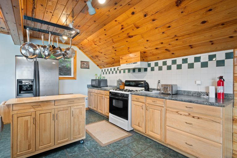 Kitchen with pot rack and gas range in Reed City, Michigan house — Lakeside Lodge Retreat, hosted by Roam