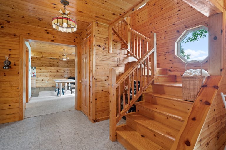 Foyer with wood staircase and octagon window in Reed City, Michigan house — Lakeside Lodge Retreat, hosted by Roam