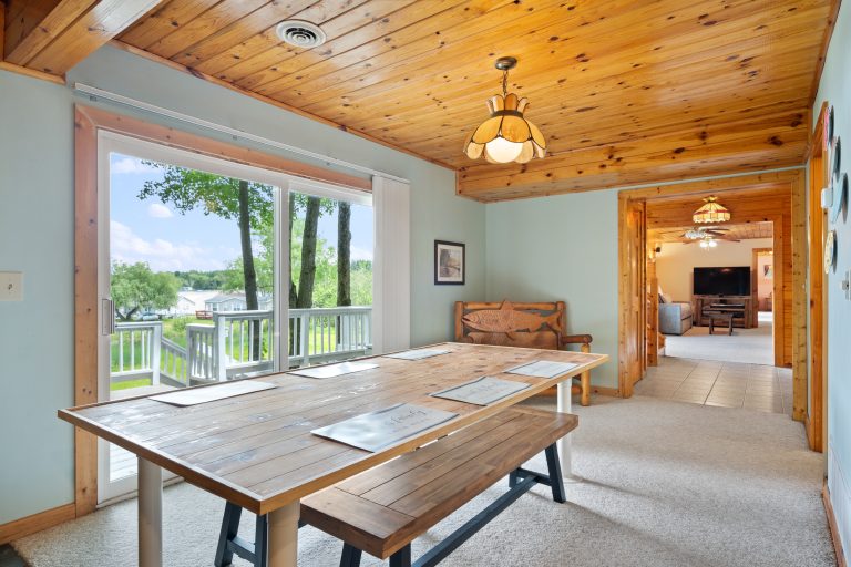 Dining area with lake view through sliding door in Reed City, Michigan house — Lakeside Lodge Retreat, hosted by Roam