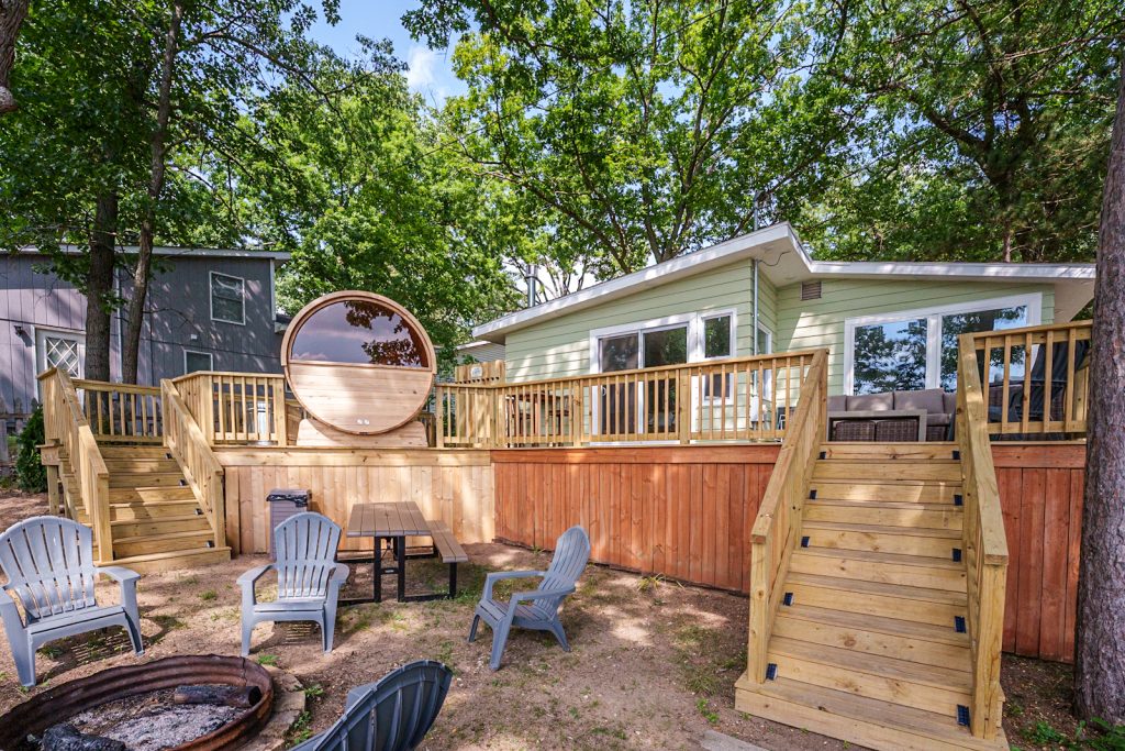 Backyard deck with barrel sauna and fire pit in this Mecosta, Michigan cabin — Silent Waters Retreat, hosted by Roam