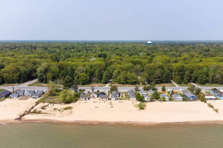 Aerial view of beachfront cabins and shoreline Cabin in Oscoda, Michigan — Barefoot Beach Cabin #3, hosted by Roam