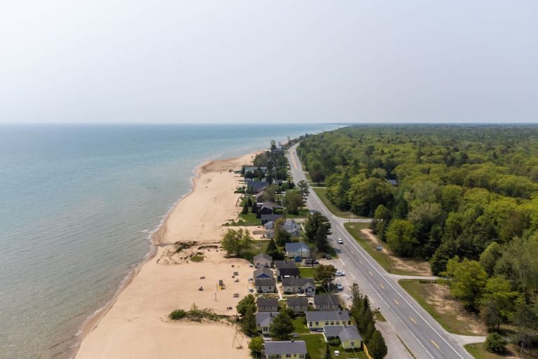 Aerial view of the Lake Huron shoreline and beach road Cabin in Oscoda, Michigan — Barefoot Beach Cabin #3, hosted by Roam