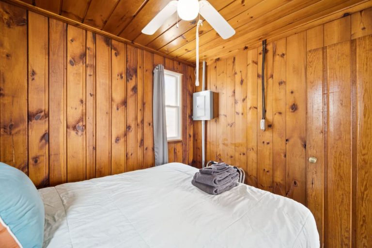 Wood-paneled bedroom with queen bed Cabin in Oscoda, Michigan — Barefoot Beach Cabin #4, hosted by Roam
