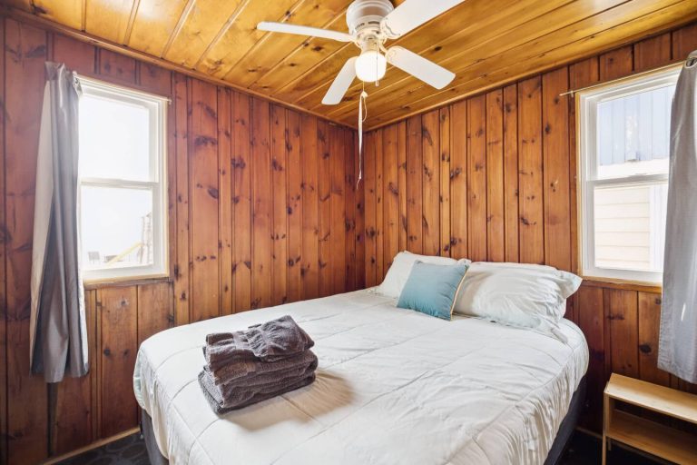 Wood-paneled bedroom with two windows Cabin in Oscoda, Michigan — Barefoot Beach Cabin #4, hosted by Roam