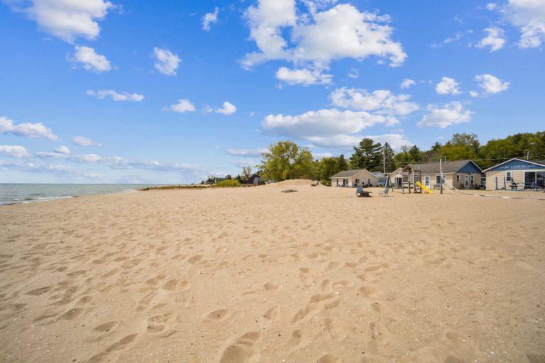 Sandy beach with cabins and playground in Oscoda, Michigan — Barefoot Beach Cabin #4, hosted by Roam