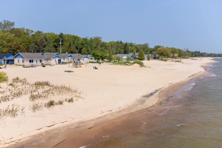 Aerial view of beachfront cabins along the shore Cabin in Oscoda, Michigan — Barefoot Beach Cabin #5, hosted by Roam
