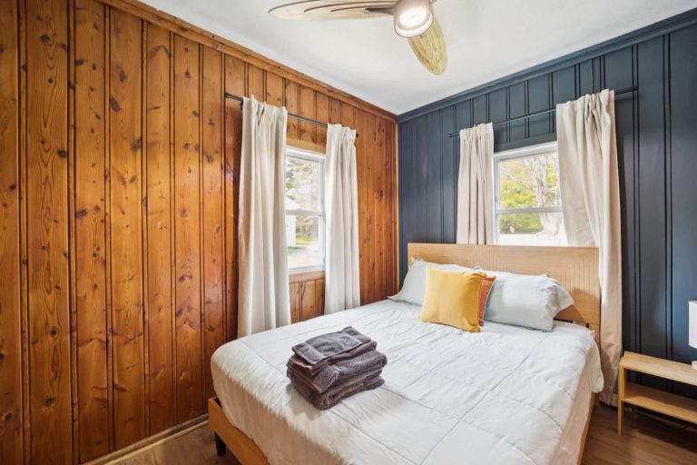 Bedroom with navy wall and wood paneling Cabin in Oscoda, Michigan — Barefoot Beach Cabin #6, hosted by Roam