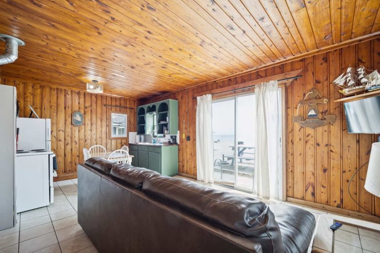 Living area with sliding door lake view Cabin in Oscoda, Michigan — Barefoot Beach Cabin #6, hosted by Roam