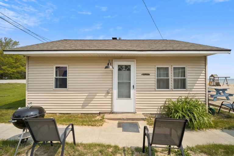 Tan-sided Cabin exterior with grill in Oscoda, Michigan — Barefoot Beach Cabin #6, hosted by Roam