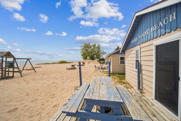 Deck with beach sign and lake view Cabin in Oscoda, Michigan — Barefoot Beach Cabin #6, hosted by Roam