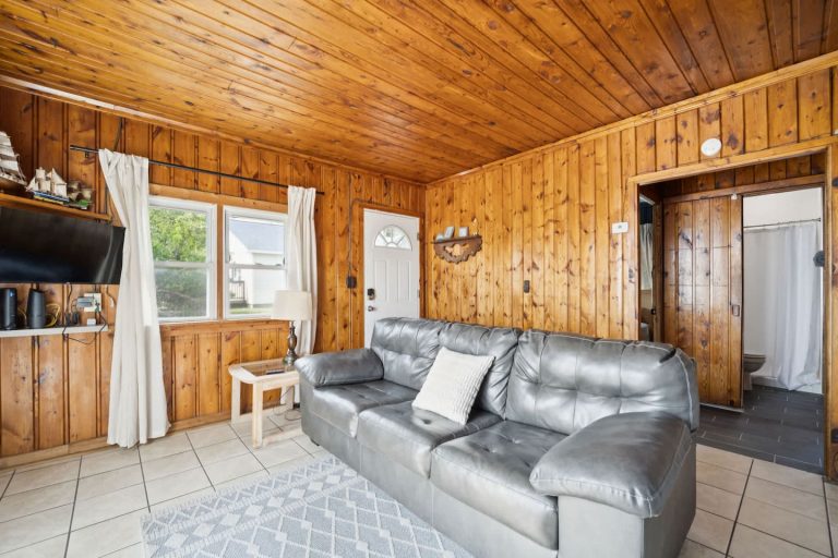 Living room with leather sofa and TV Cabin in Oscoda, Michigan — Barefoot Beach Cabin #6, hosted by Roam