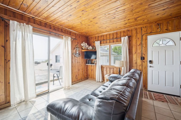 Living room with sliding door lake view Cabin in Oscoda, Michigan — Barefoot Beach Cabin #6, hosted by Roam