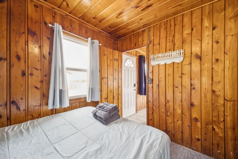 Wood-paneled bedroom near entry Cabin in Oscoda, Michigan — Barefoot Beach Cabin #7, hosted by Roam