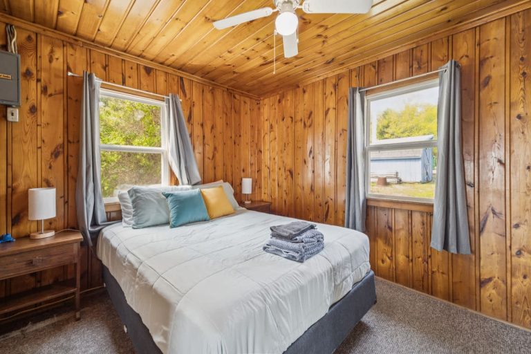 Bedroom with two curtained windows Cabin in Oscoda, Michigan — Barefoot Beach Cabin #7, hosted by Roam