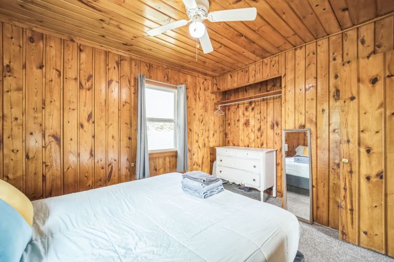 Wood-paneled bedroom with mirror Cabin in Oscoda, Michigan — Barefoot Beach Cabin #7, hosted by Roam