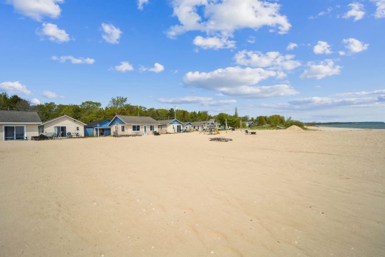 Beach view of cottage row Cabin in Oscoda, Michigan — Barefoot Beach Cabin #7, hosted by Roam