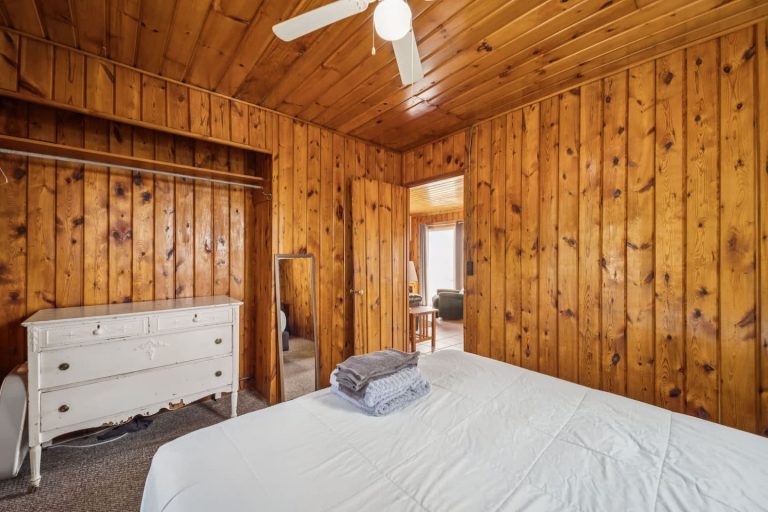 Wood-paneled bedroom with dresser Cabin in Oscoda, Michigan — Barefoot Beach Cabin #7, hosted by Roam
