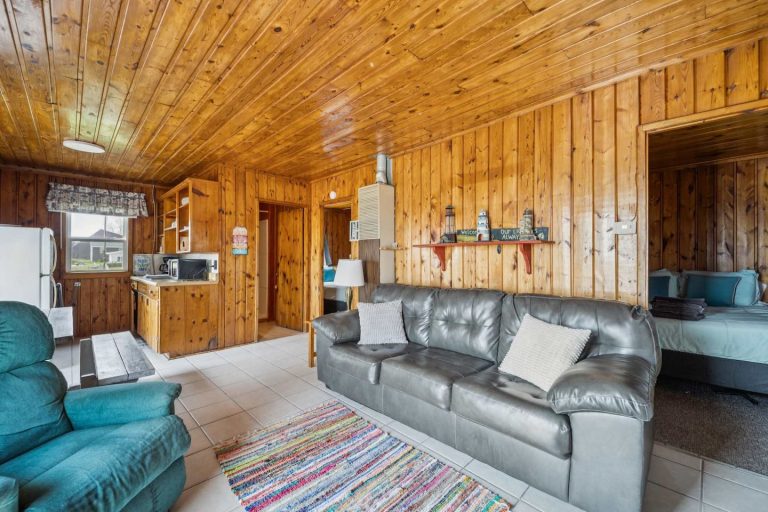 Living room with teal recliner Cabin in Oscoda, Michigan — Barefoot Beach Cabin #7, hosted by Roam
